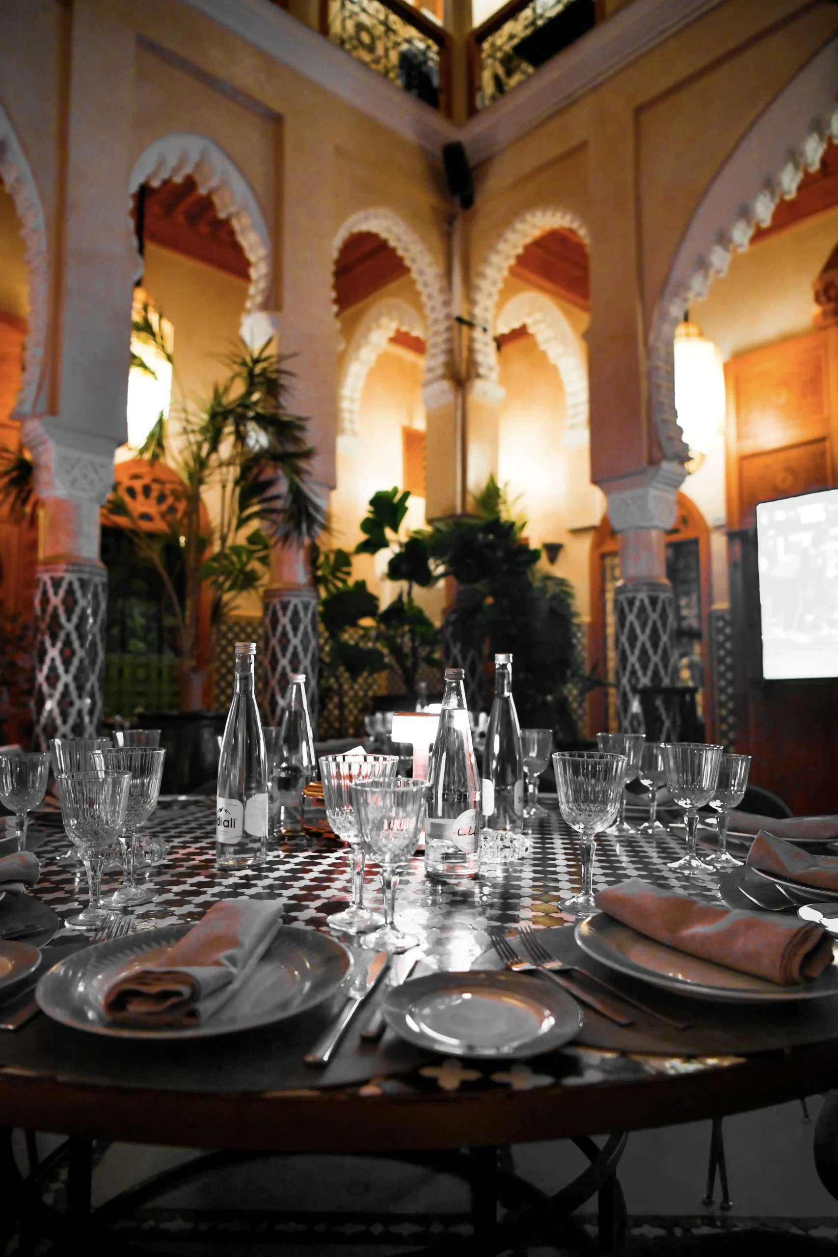 ntérieur élégant du restaurant avec une architecture marocaine raffinée, des arches majestueuses, des tables élégamment dressées, et une ambiance chaleureuse, mettant en valeur l'élégance architecturale du lieu.