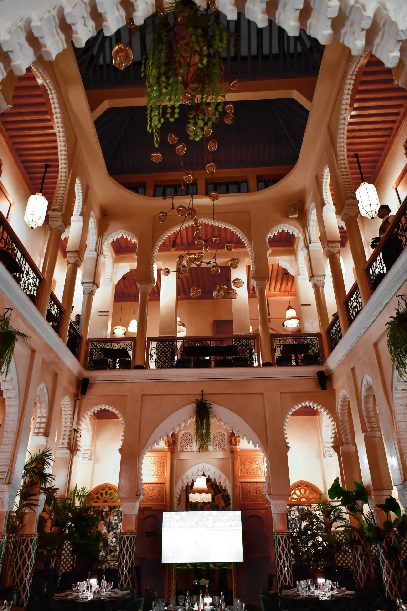 ntérieur élégant du restaurant avec une architecture marocaine raffinée, des arches majestueuses, des tables élégamment dressées, et une ambiance chaleureuse, mettant en valeur l'élégance architecturale du lieu.