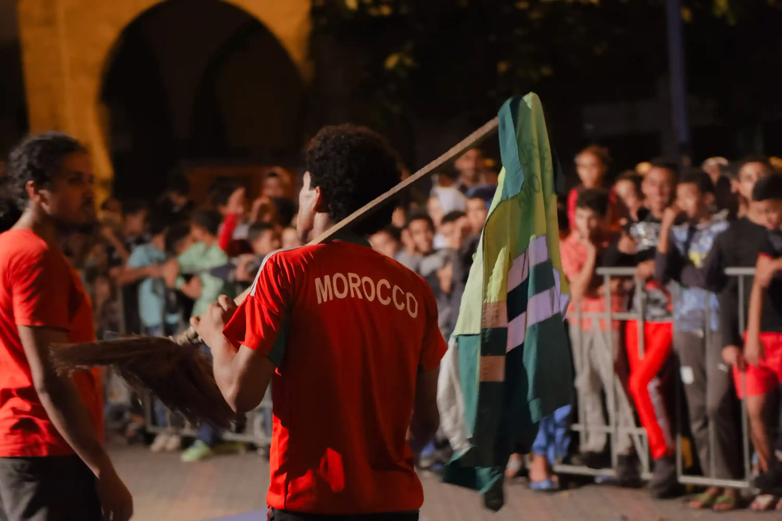 Photographie de danseur de danse urbaine en action, avec des lumières colorées illuminant la scène et un public énergique en arrière-plan.